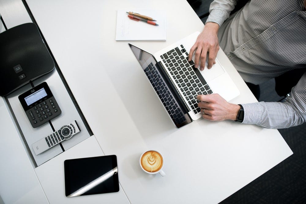 person using laptop on white wooden table person using laptop on white wooden table