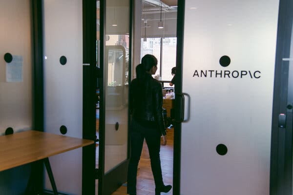 A figure walks away from the camera and into another room through a frosted glass door. The name “Anthropic” appears on the closed half of the door. 