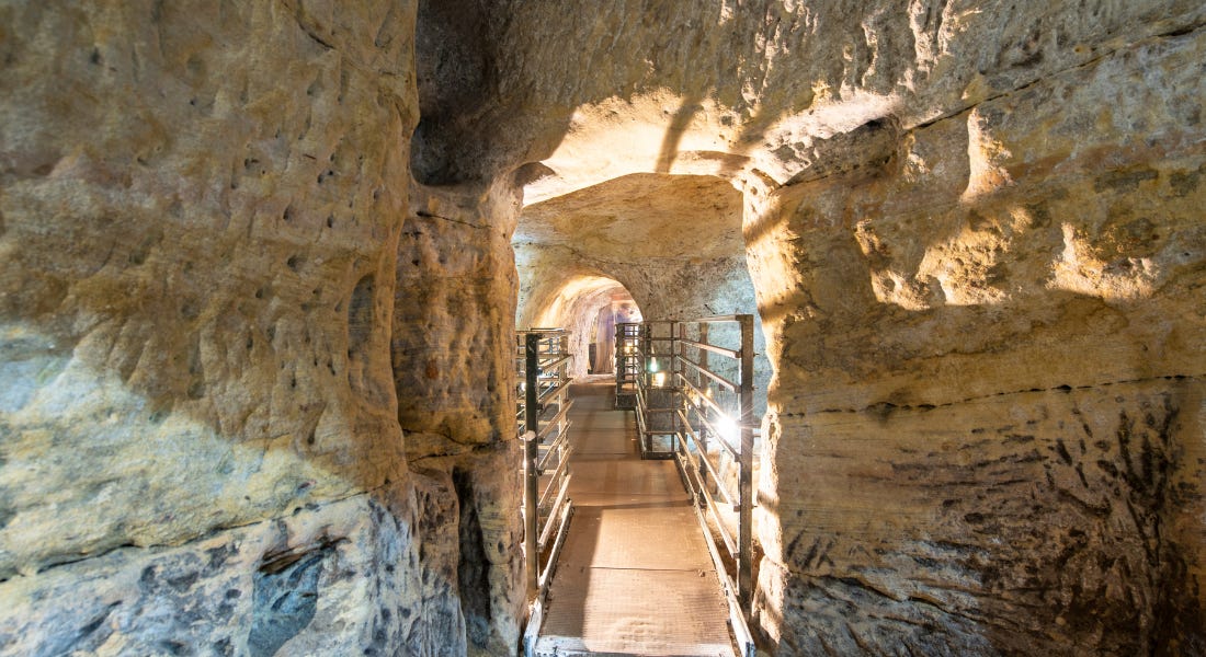 The inside of a cave with a wooden path running through the middle of it The inside of a cave with a wooden path running through the middle of it