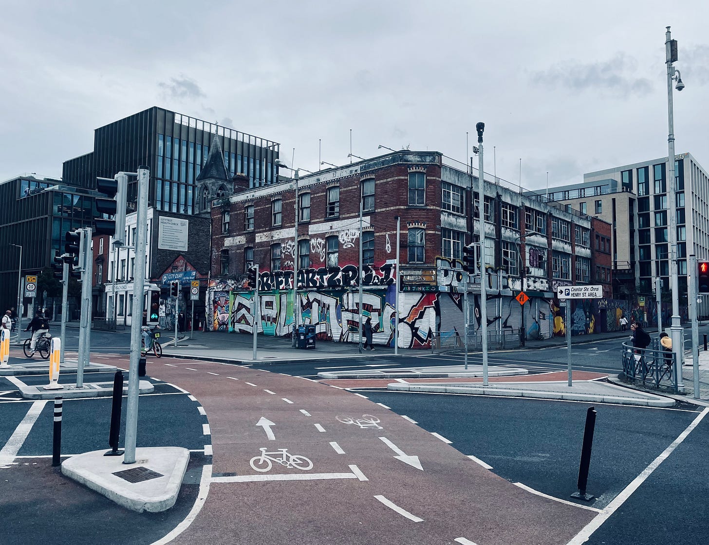 A street with a brick building and graffiti on the side

Description automatically generated