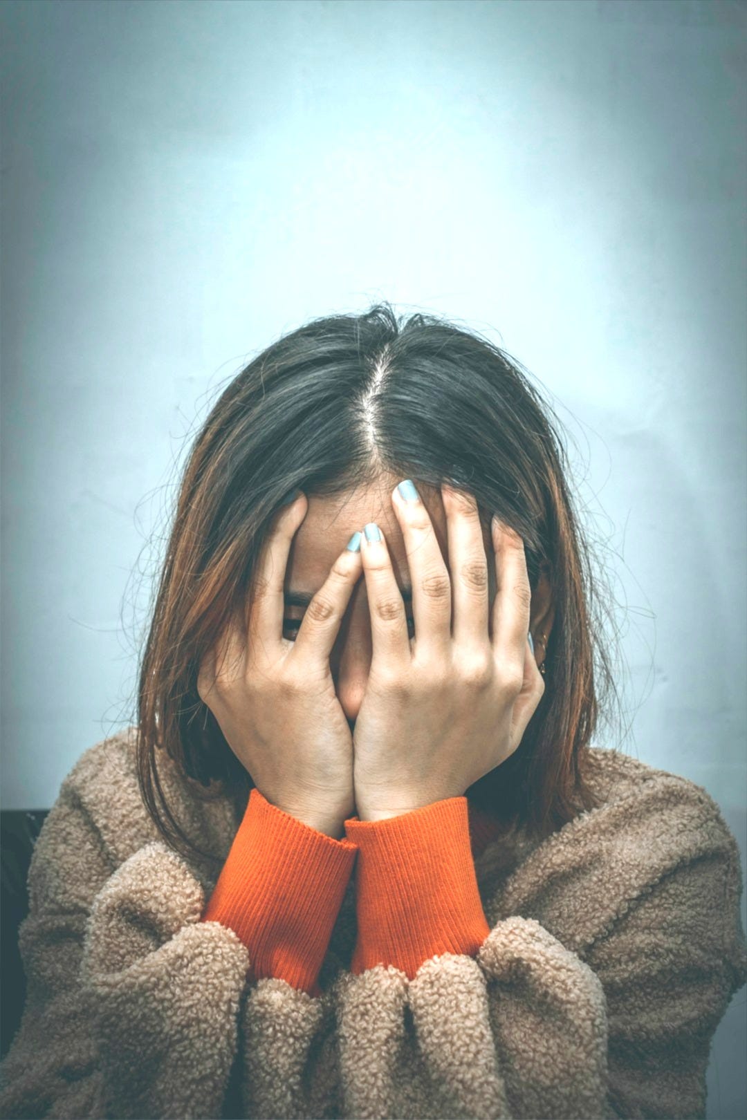 woman in brown sweater covering her face with her hand woman in brown sweater covering her face with her hand