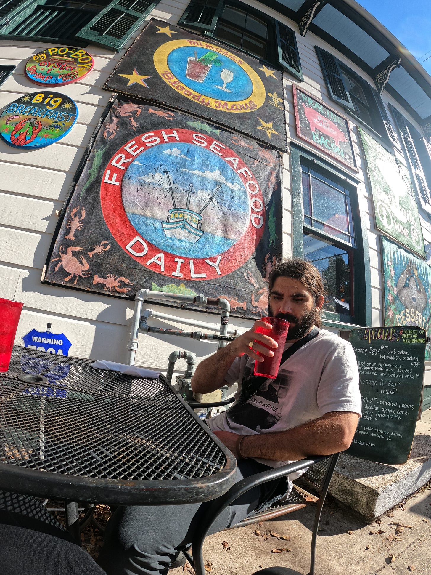 Anthony sipping on his drink sitting in the hot sun outside at Elizabeth's Restaurant