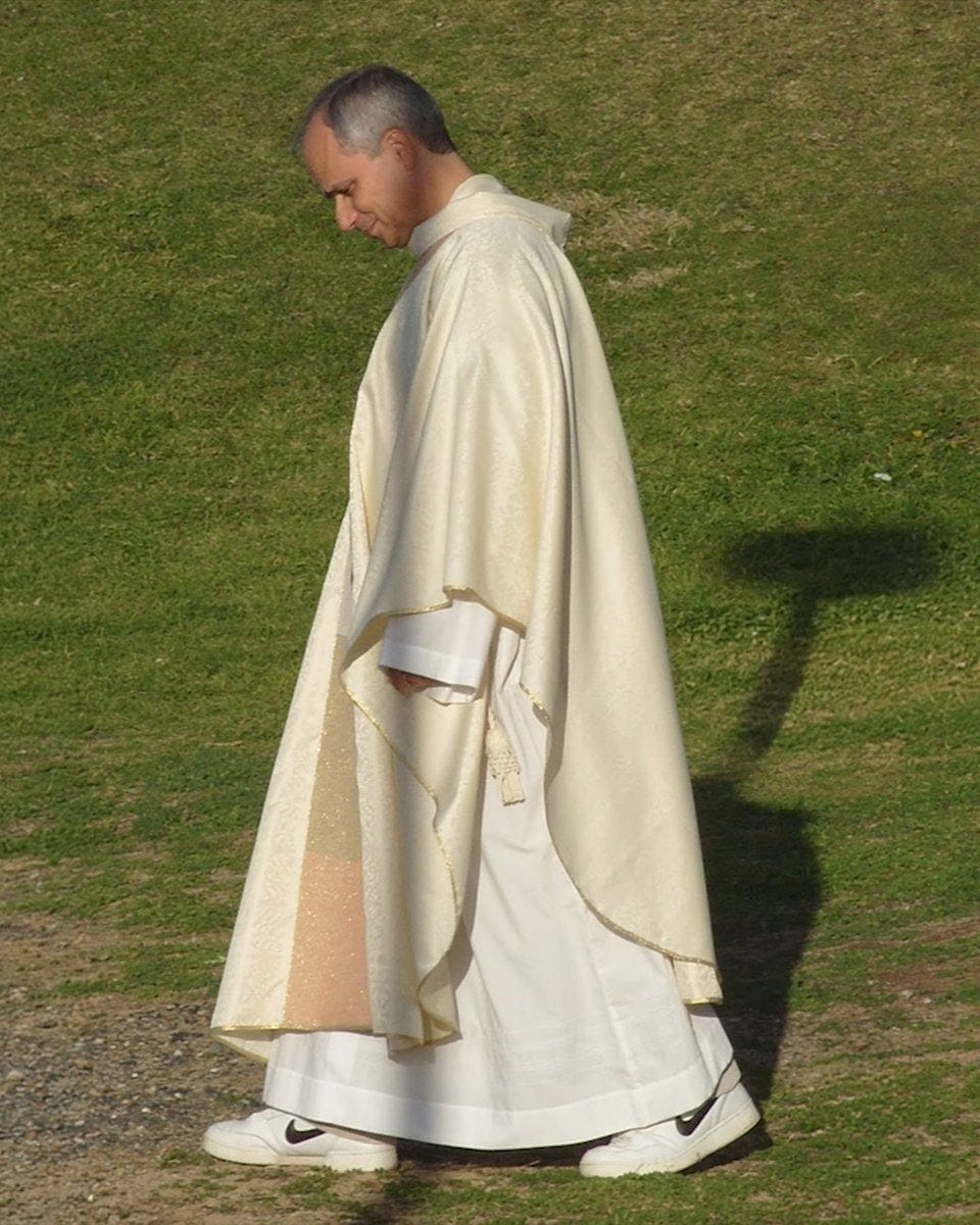 Robert Prevost walking across grass in a cream chasuble and white Nike sneakers Robert Prevost walking across grass in a cream chasuble and white Nike sneakers