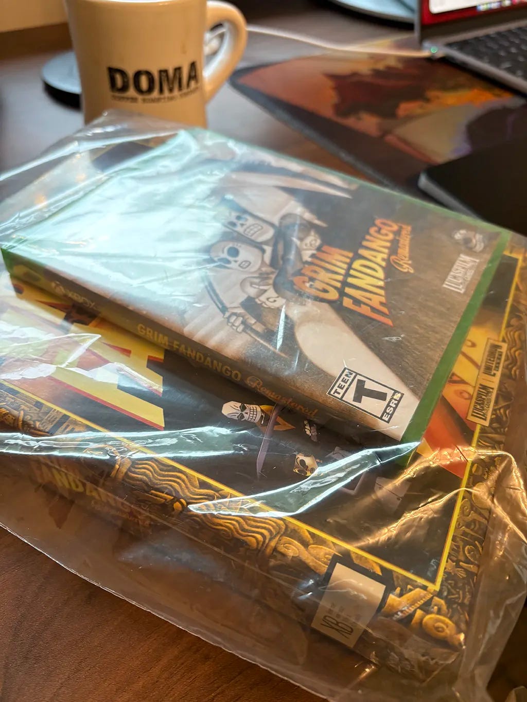 Grim Fandango on a desk with a coffee cup in the back