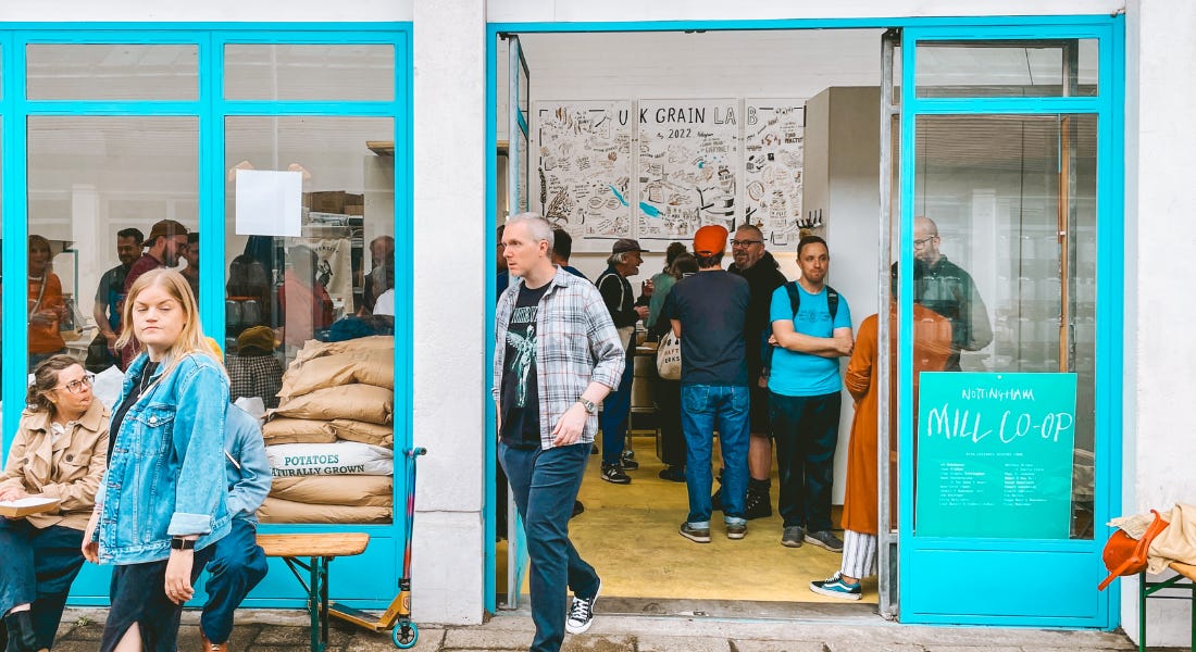A blue and white building with an open door and people walking out of it and into it