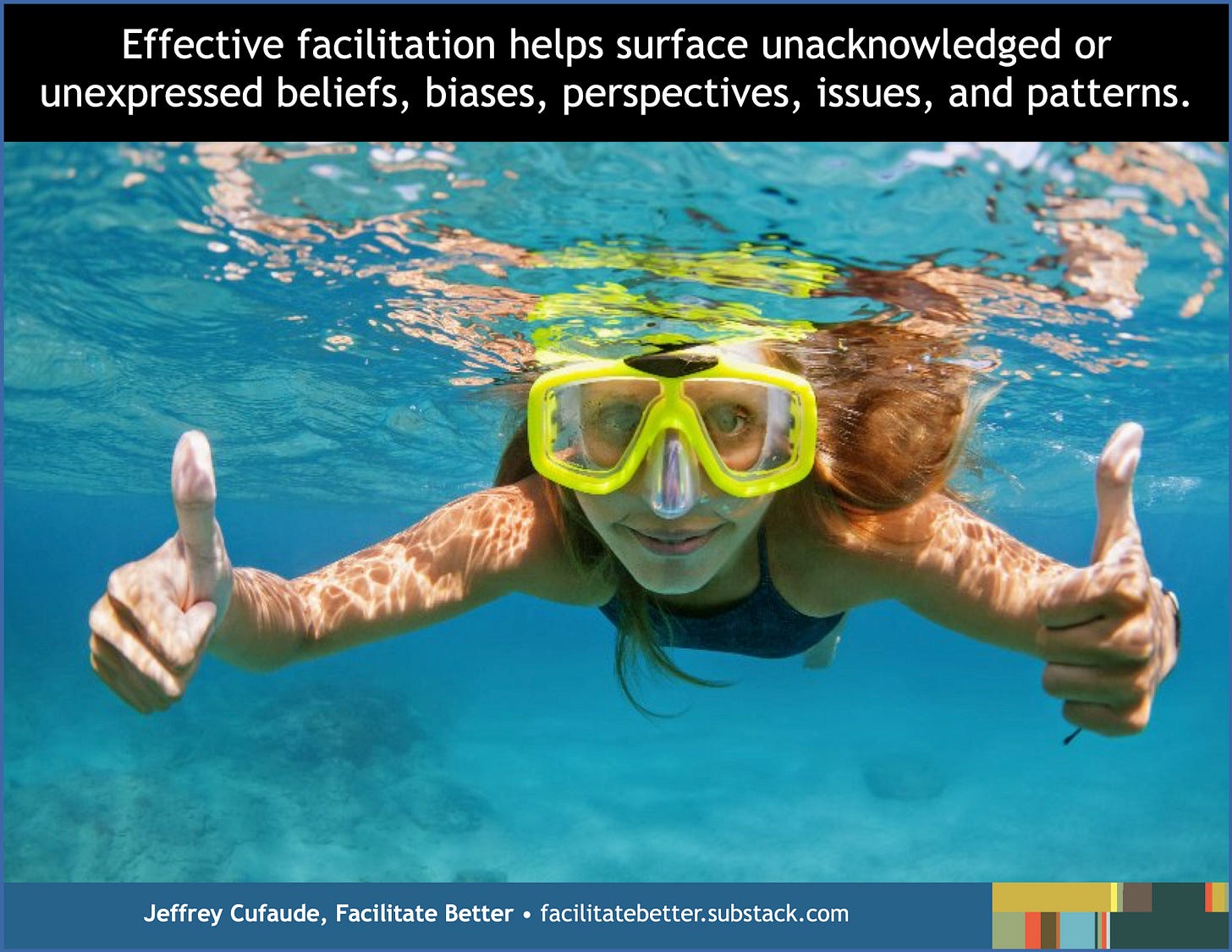 Closeup of a young female diver wearing goggles and just beneath the water’s surface.  She is giving two thumbs up and smiling.