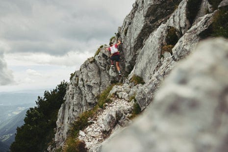 Ultrarunner Sophie Woods scales a steep alpine trail using a cable handhold above a valley Ultrarunner Sophie Woods scales a steep alpine trail using a cable handhold above a valley