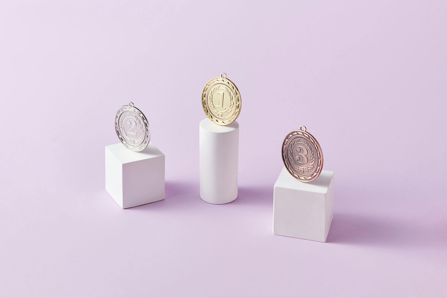 First, second, and third place medal sitting on pedestals ranging in height.