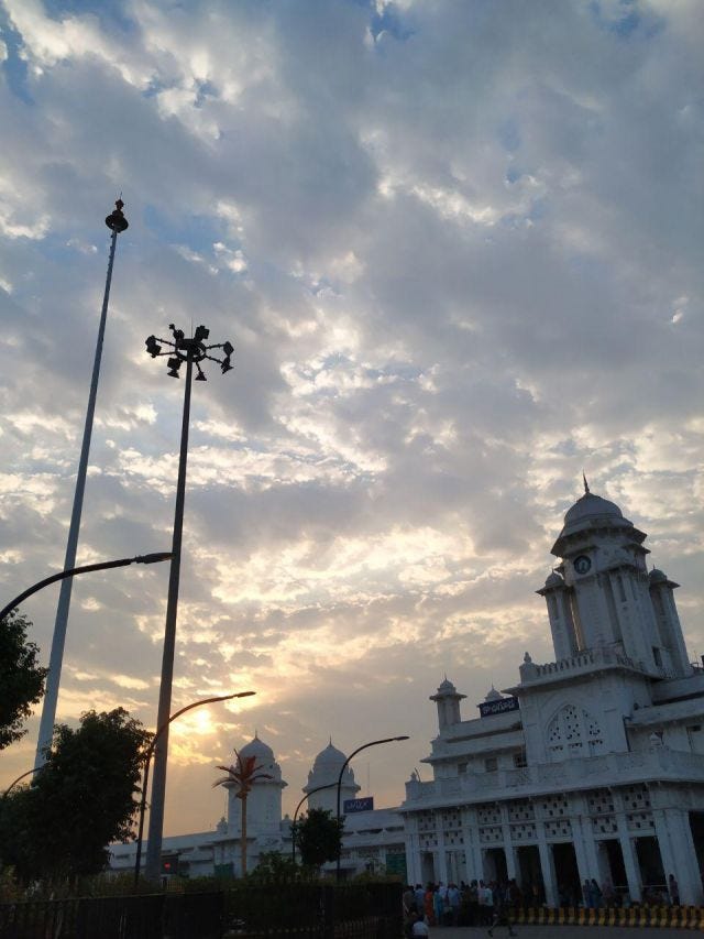 An early morning shot of clouds and sun rising behind the old built kacheguda station. A night lamp stands in the middle of the road. An early morning shot of clouds and sun rising behind the old built kacheguda station. A night lamp stands in the middle of the road.