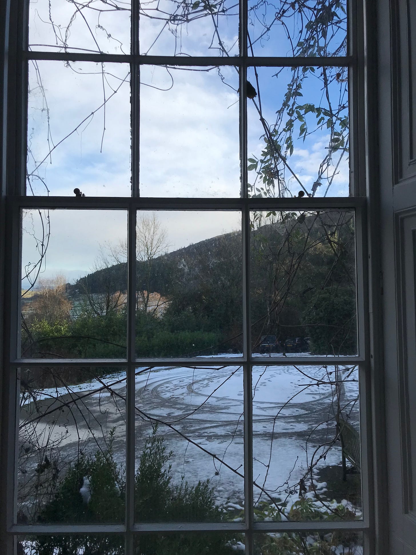 view through a window, with snow and hills in the distance.