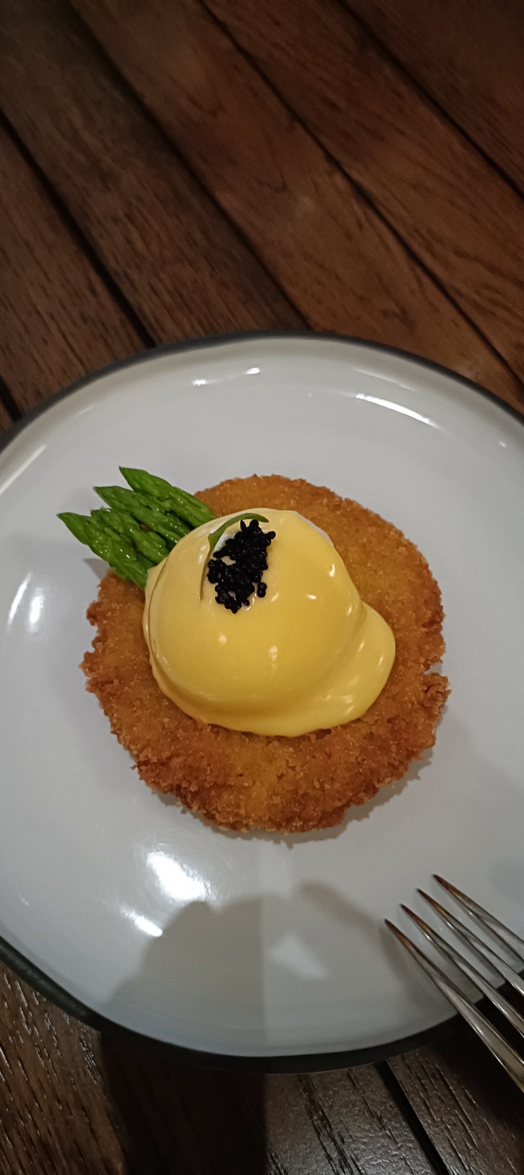 A plate of Crispy Crab Cake and Caviar topped with a poached egg and hollandaise sauce