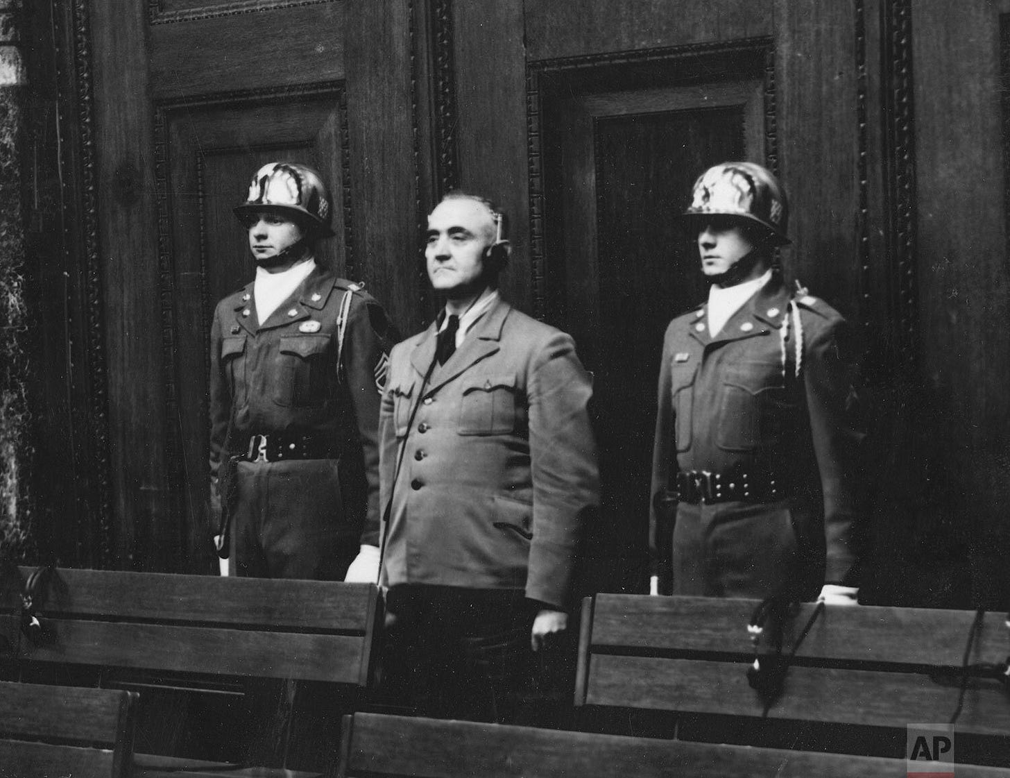 Gottlob Berger, former chief of the SS head office, is sentenced to 25 years in prison, escorted by Sgt. Thomas H. Andress and an unidentified honor guard during the Nuremberg proceedings.