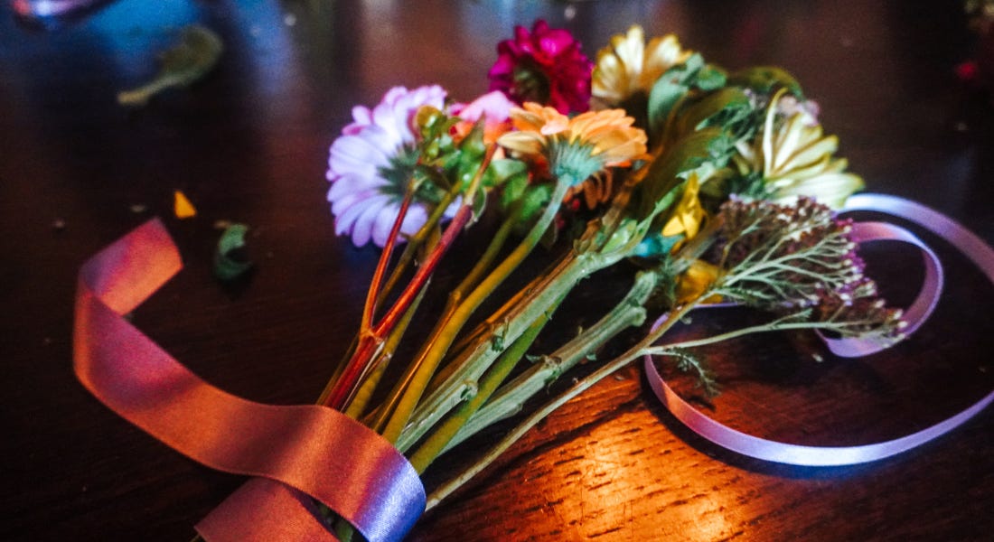 A dark wooden table with a bouquet wrapped in ribbons A dark wooden table with a bouquet wrapped in ribbons