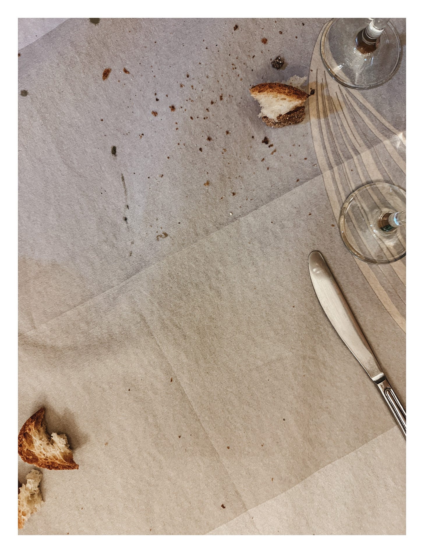 rustic bread and breadcrumbs on a linen table cloth after dinner scattered between cutlery and glasses
