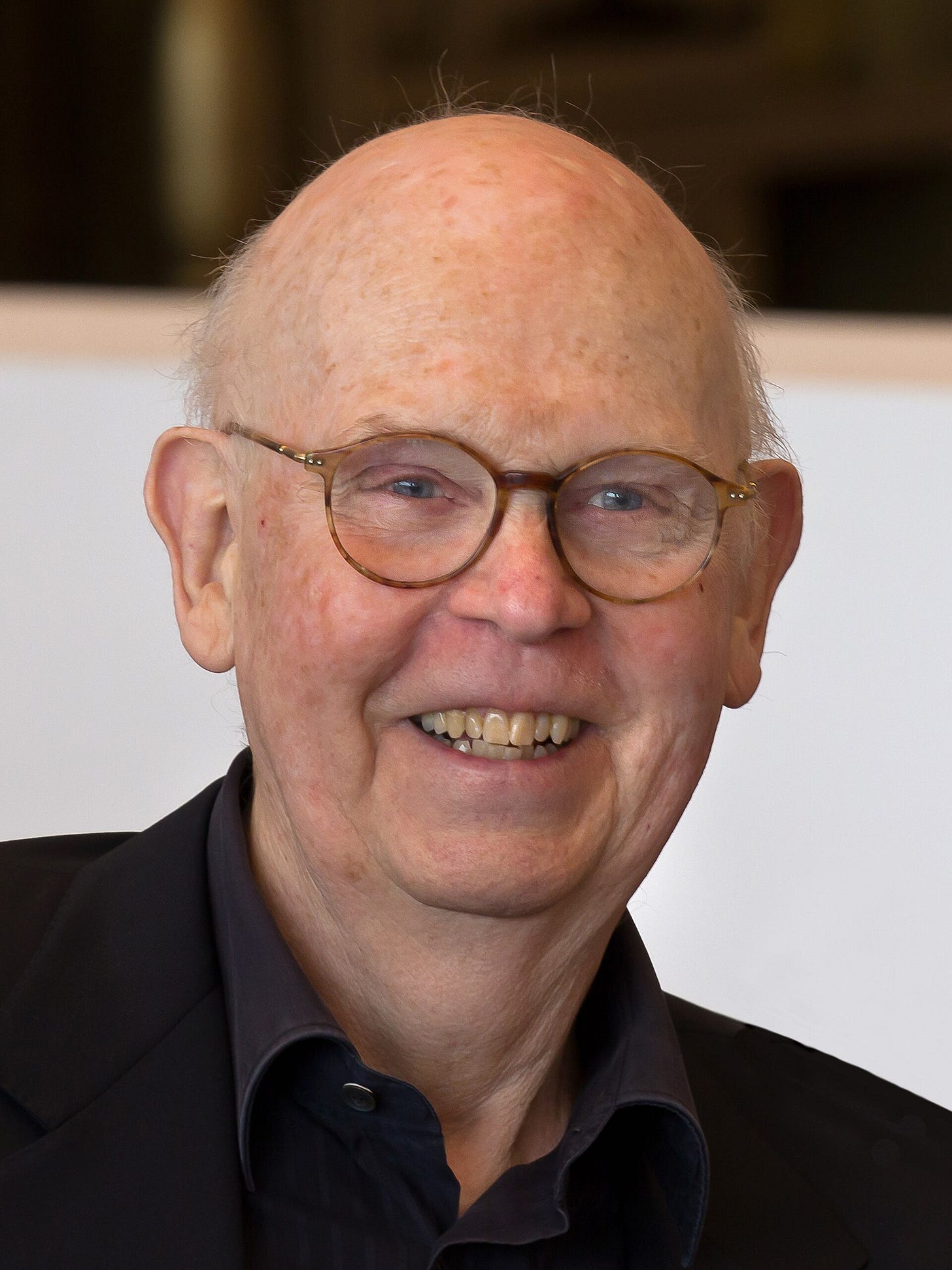 Claes Oldenburg, bald and smiling behind round glasses, in a dark jacket in 2012. Claes Oldenburg, bald and smiling behind round glasses, in a dark jacket in 2012.