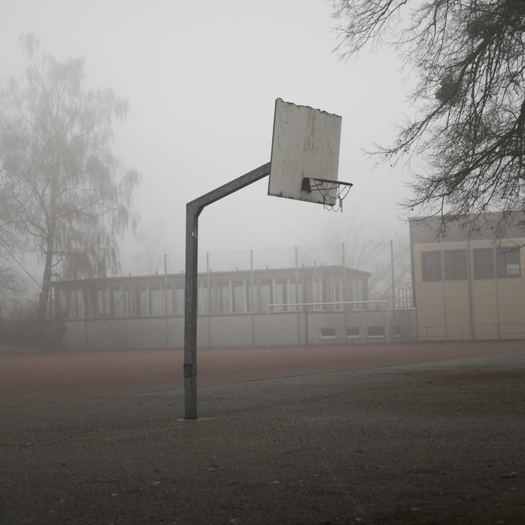 Basketball hoop on a foggy day outdoors.
