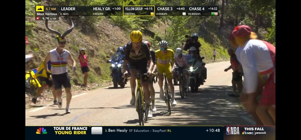Tiesj Benoot, Jonas Vingegaard and Tadej Pogacar climbing Mont Ventoux, escorted by a swole guy in a sleeveless world championship cycling jersey and a football helmet adorned by...are those ibex horns?