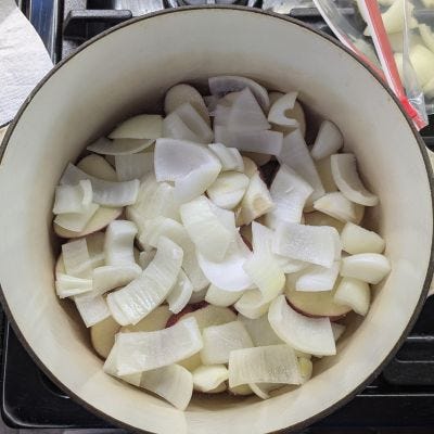 Picture of first potatoes, then onions, then carrots and meat in the pot