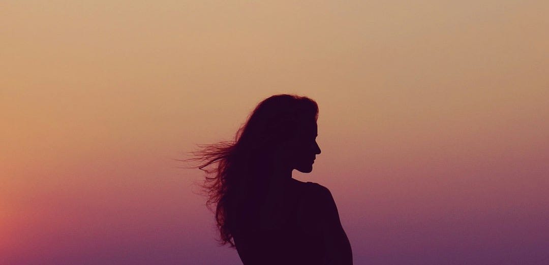silhouette of woman under orange sky silhouette of woman under orange sky