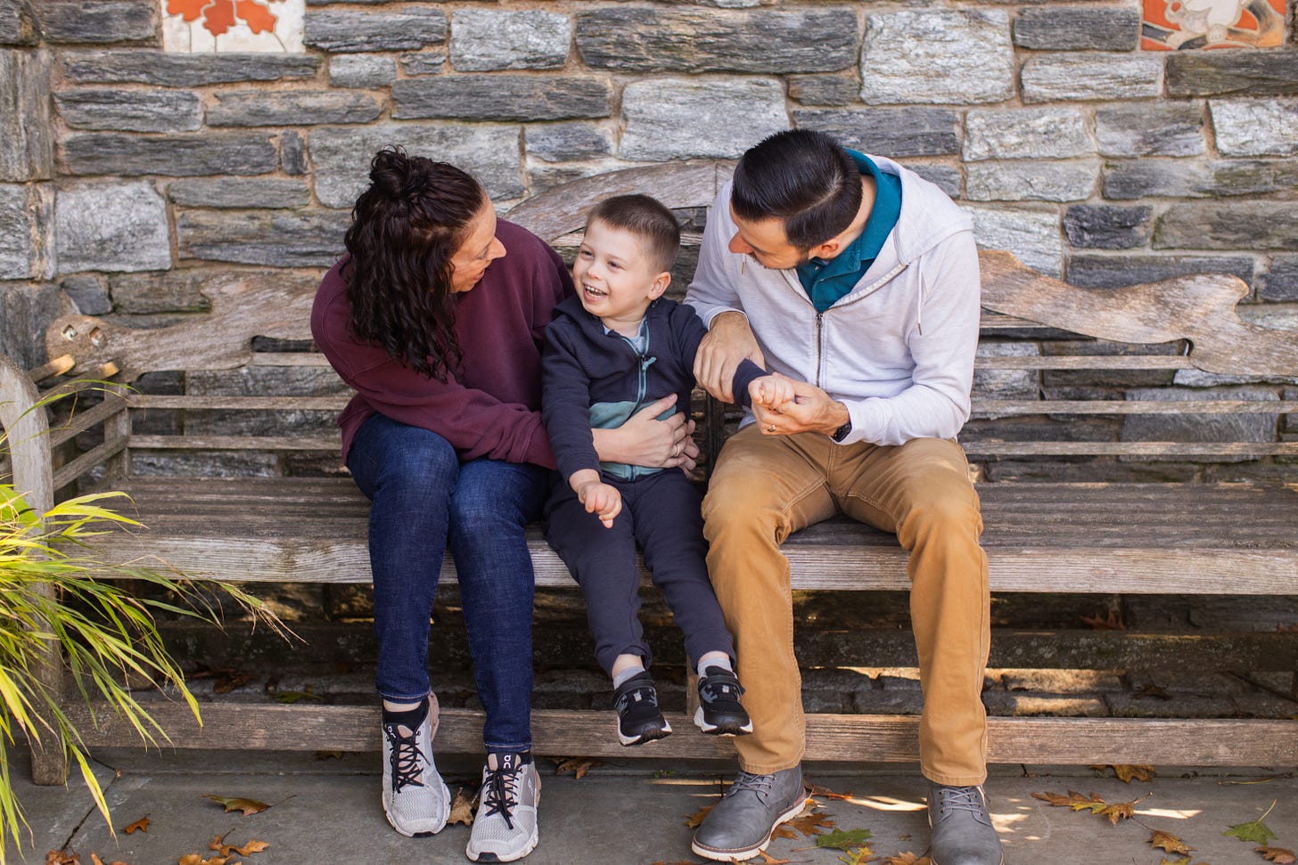 A family sitting on a bench at an arboretum.