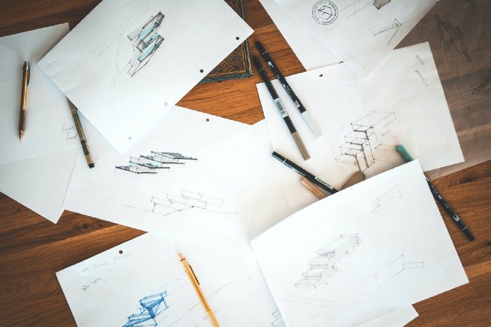 A table filled with paper sketches of varying completeness and fidelity. A table filled with paper sketches of varying completeness and fidelity.