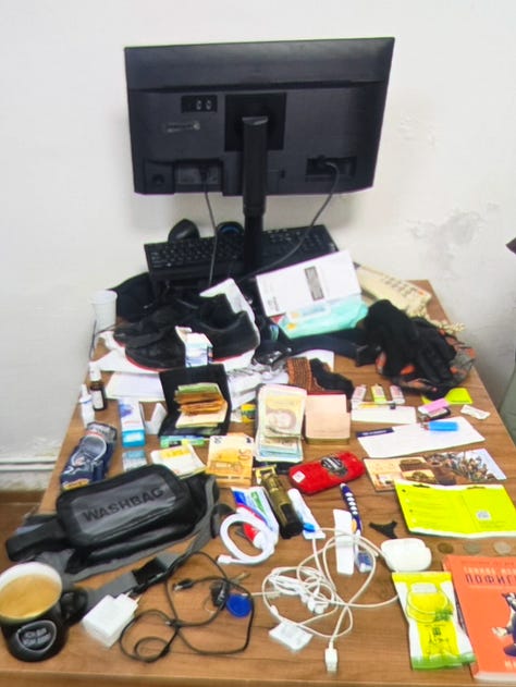 Dëshmia #1 – Paketime SIM: Kartela SIM dhe paketime aktivizimi të fotografuara si pjesë e inventarit, me kodet e sigurisë të redaktuara. | Dëshmia #2 – Harta dhe materiale të shtypura: Harta rajonale dhe dokumente letre të sekuestruara, që sugjerojnë planifikim lëvizjeje ose reference terreni. | Dëshmia #3 – Para dhe sende personale: Para të gatshme, dokumente dhe objekte personale të shtrira gjatë inventarizimit zyrtar. | Dëshmia #4 – Telefona dhe pajisje elektronike: Telefona të shumtë, karta memorie dhe pajisje të lidhura, të etiketuar si prova. | Dëshmia #5 – Mjete teknike dhe mjete ndihmëse: Kabllo, module elektronike dhe mjete të tjera ndihmëse, që tejkalojnë përdorimin bazik personal.