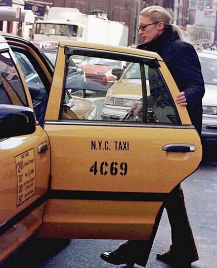 This may contain: a woman walking past a taxi cab in new york city