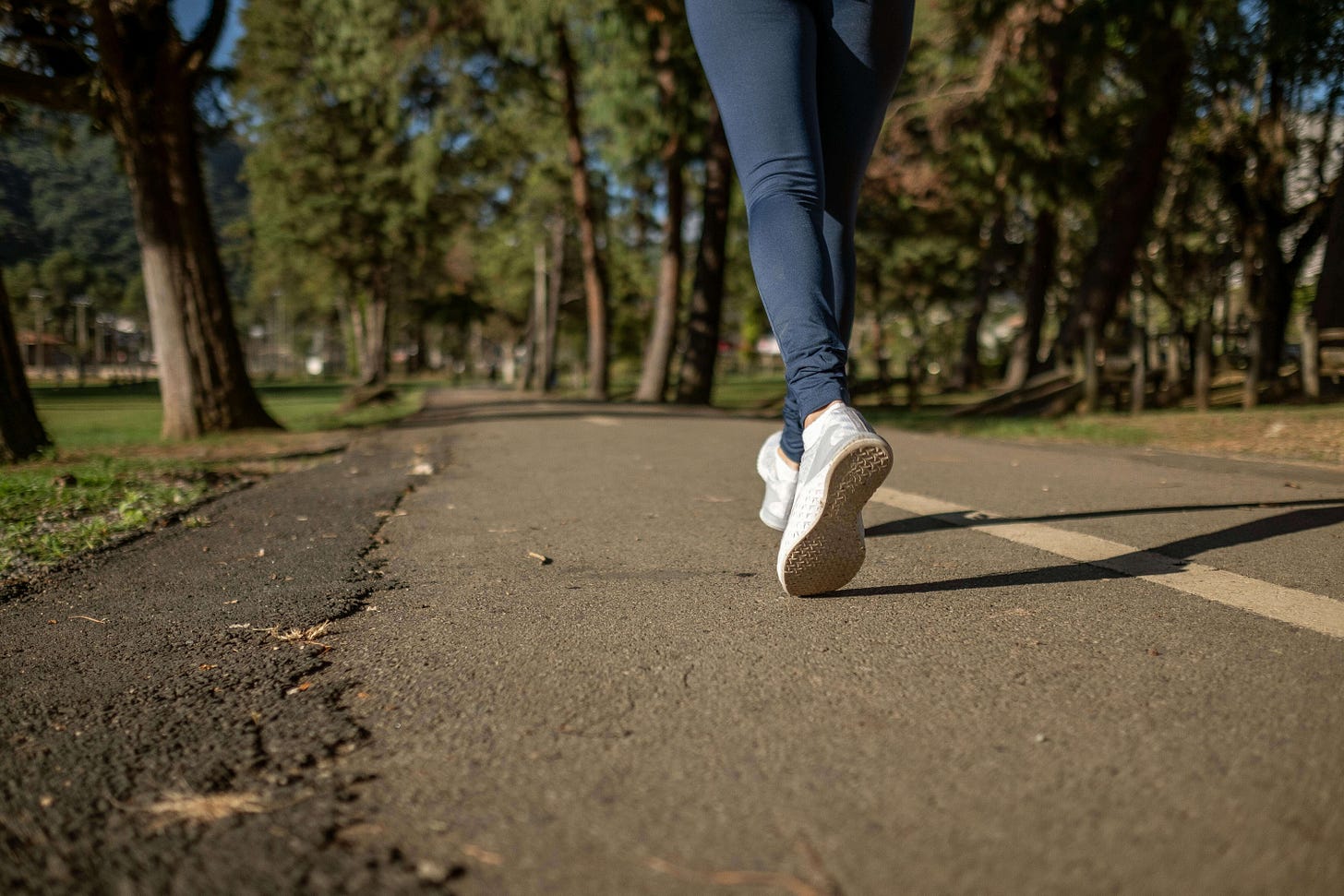 Person taking a relaxed walk on a wooded path, illustrating active recovery through light movement.