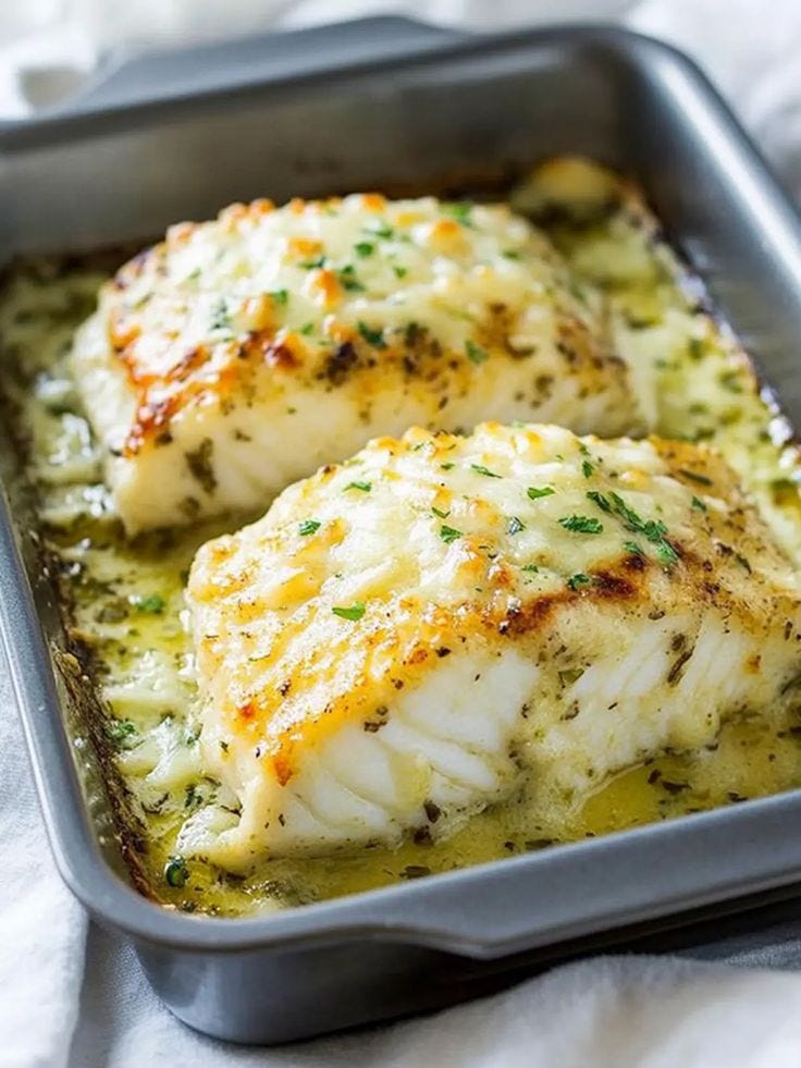 This may contain: two fish fillets in a pan with cheese and herbs