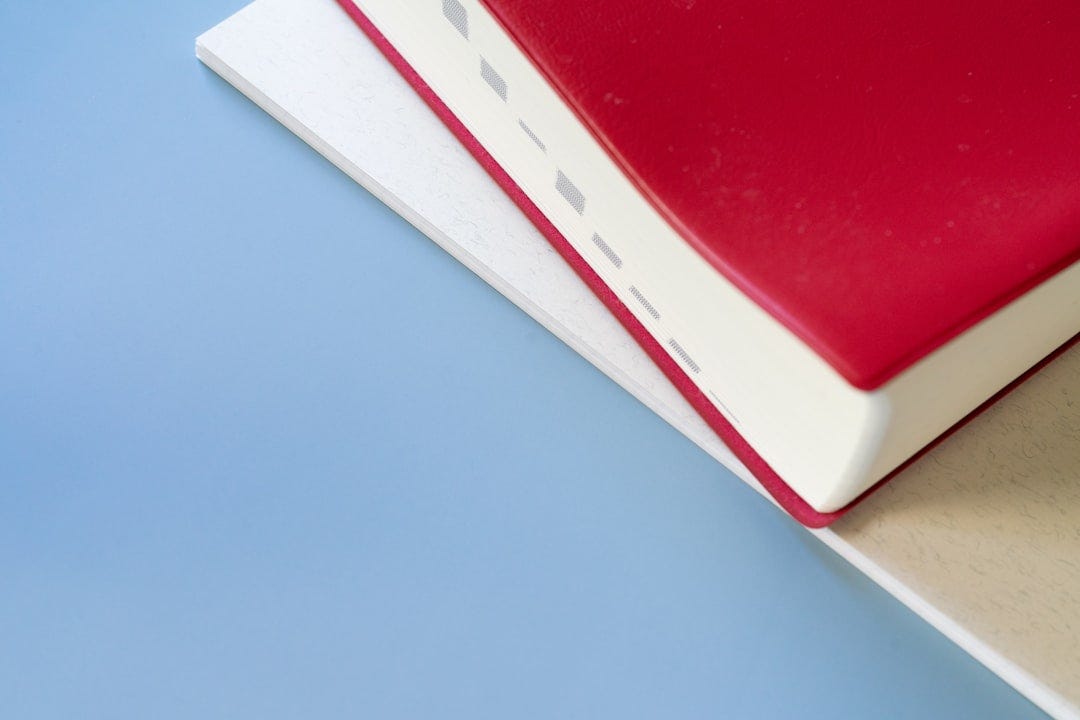 A red book sitting on top of a white book A red book sitting on top of a white book