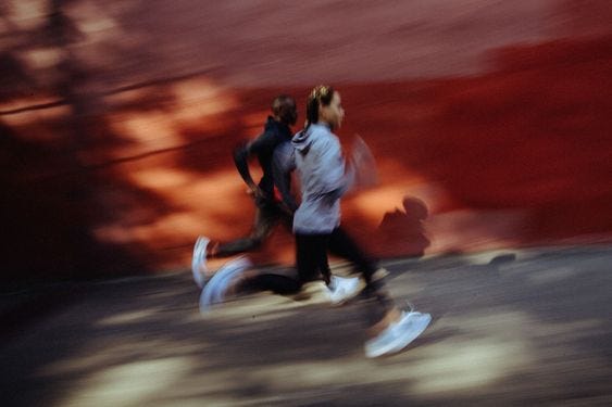 A blurry image of two humans running in athleisure. A blurry image of two humans running in athleisure.