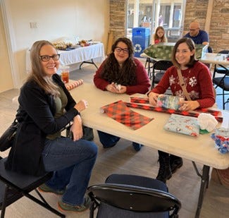Left: Two women wrap Christmas gifts with red and black plaid paper. Right: Several people form an assembly line for wrapping Christmas gifts along a table.
