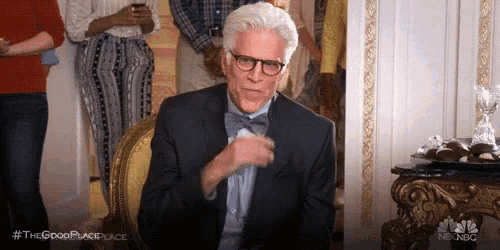 a man in a suit and bow tie is sitting in a chair in front of a crowd . a man in a suit and bow tie is sitting in a chair in front of a crowd .