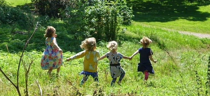 This may contain: three children are running in the grass holding hands