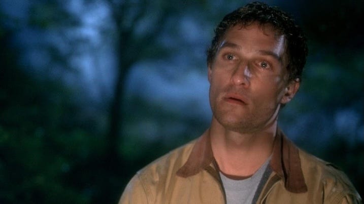 Close-up of Matthew McConaughey in a forest at night, looking offscreen with a solemn expression.