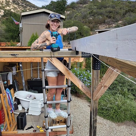 Up on the ladder, roofing the patio outside my tiny house!