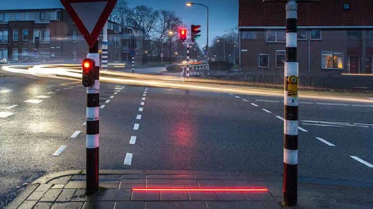A street with traffic lights and a red light

Description automatically generated