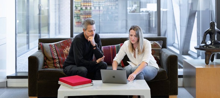 Two people sitting on couch looking at laptop