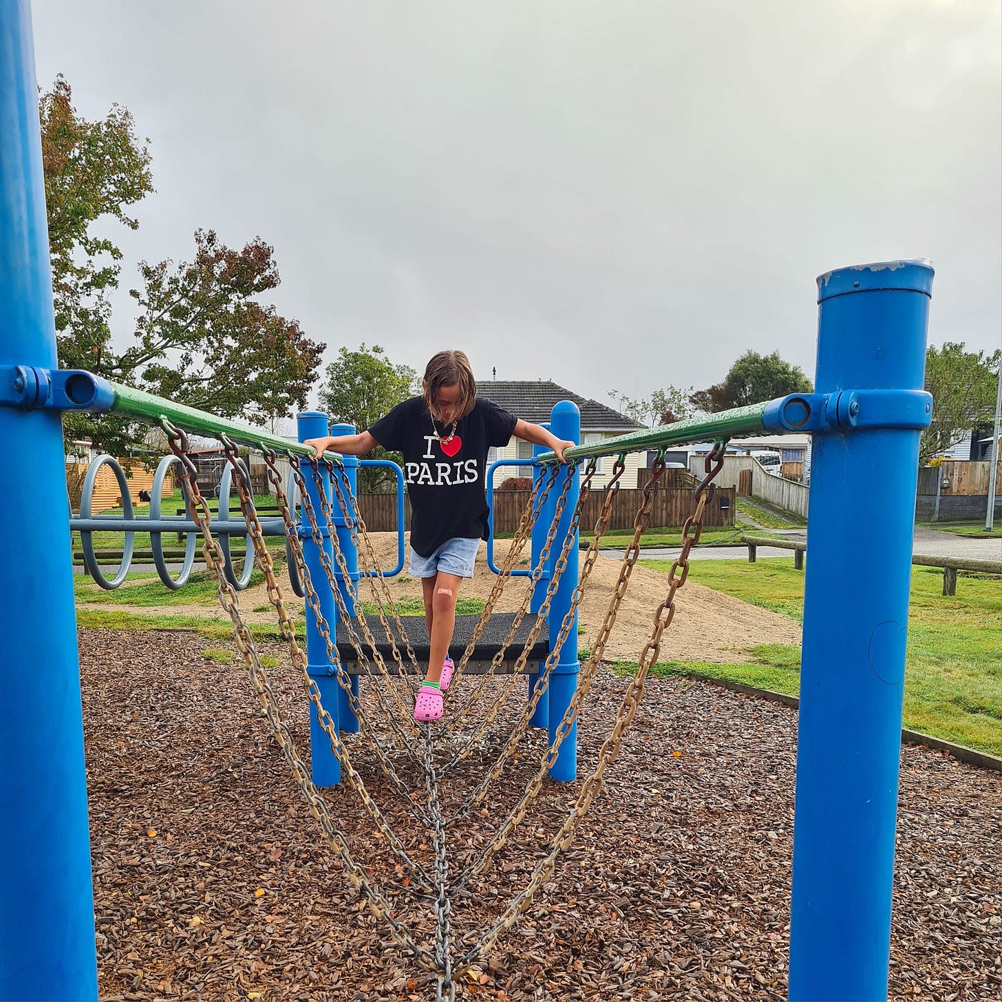 a young child navigates a chain link balance on a playground
