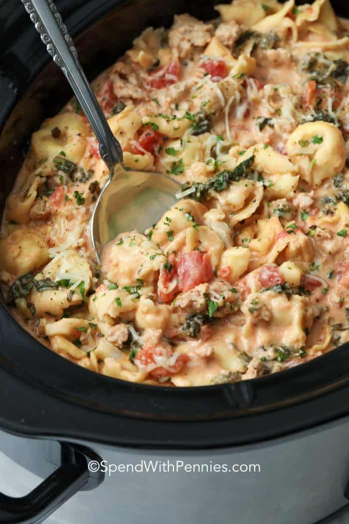 Spooning Creamy Crockpot Tortellini out of a crockpot