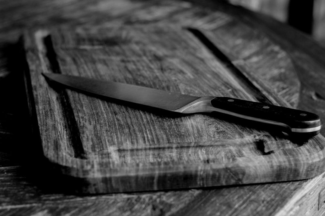 black handled knife on brown wooden chopping board black handled knife on brown wooden chopping board
