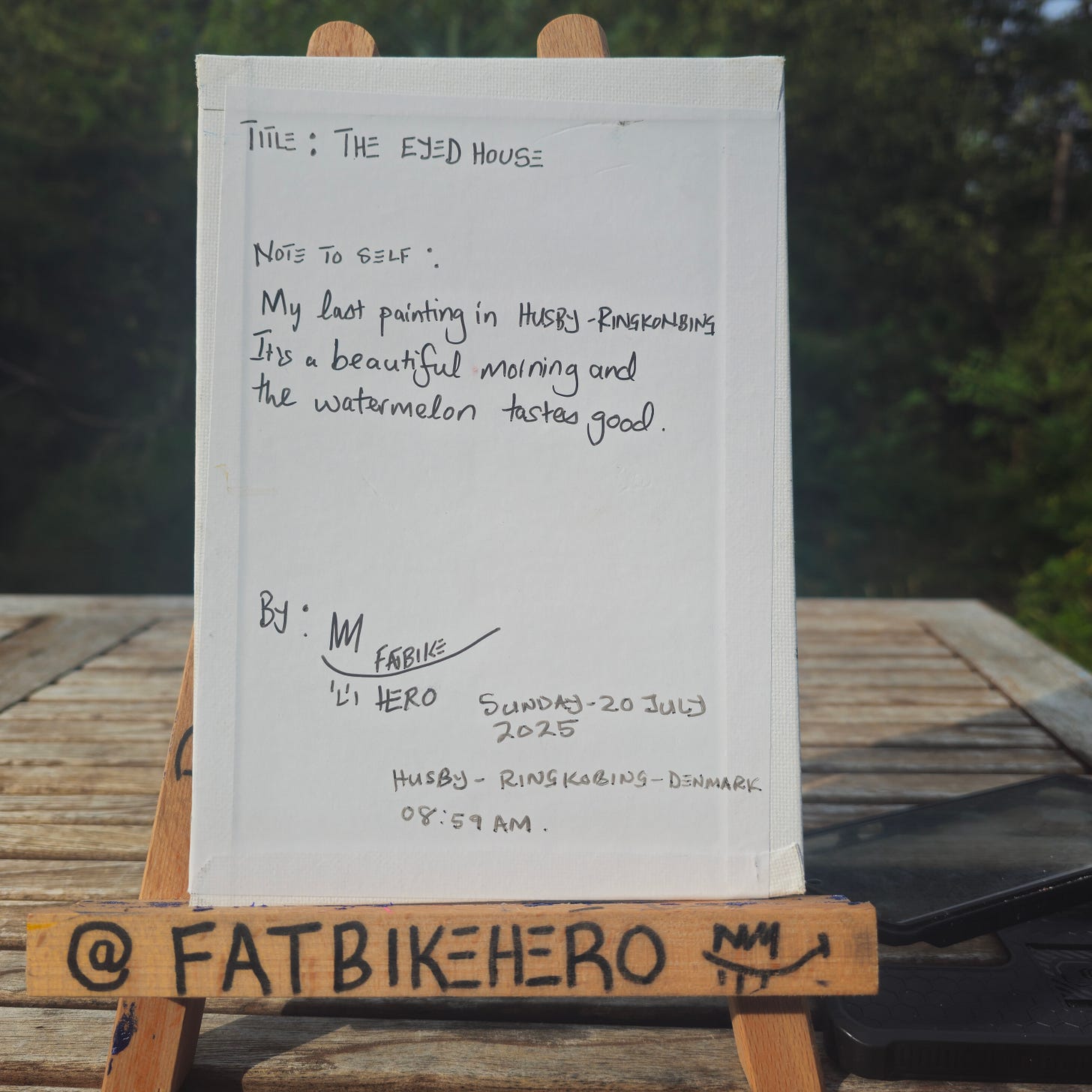 Back of The Eyed House canvas by FatbikeHero showing handwritten title, note about painting in Husby–Ringkøbing, signature, date Sunday 20 July 2025, time 08:59 AM, and location Denmark Back of The Eyed House canvas by FatbikeHero showing handwritten title, note about painting in Husby–Ringkøbing, signature, date Sunday 20 July 2025, time 08:59 AM, and location Denmark