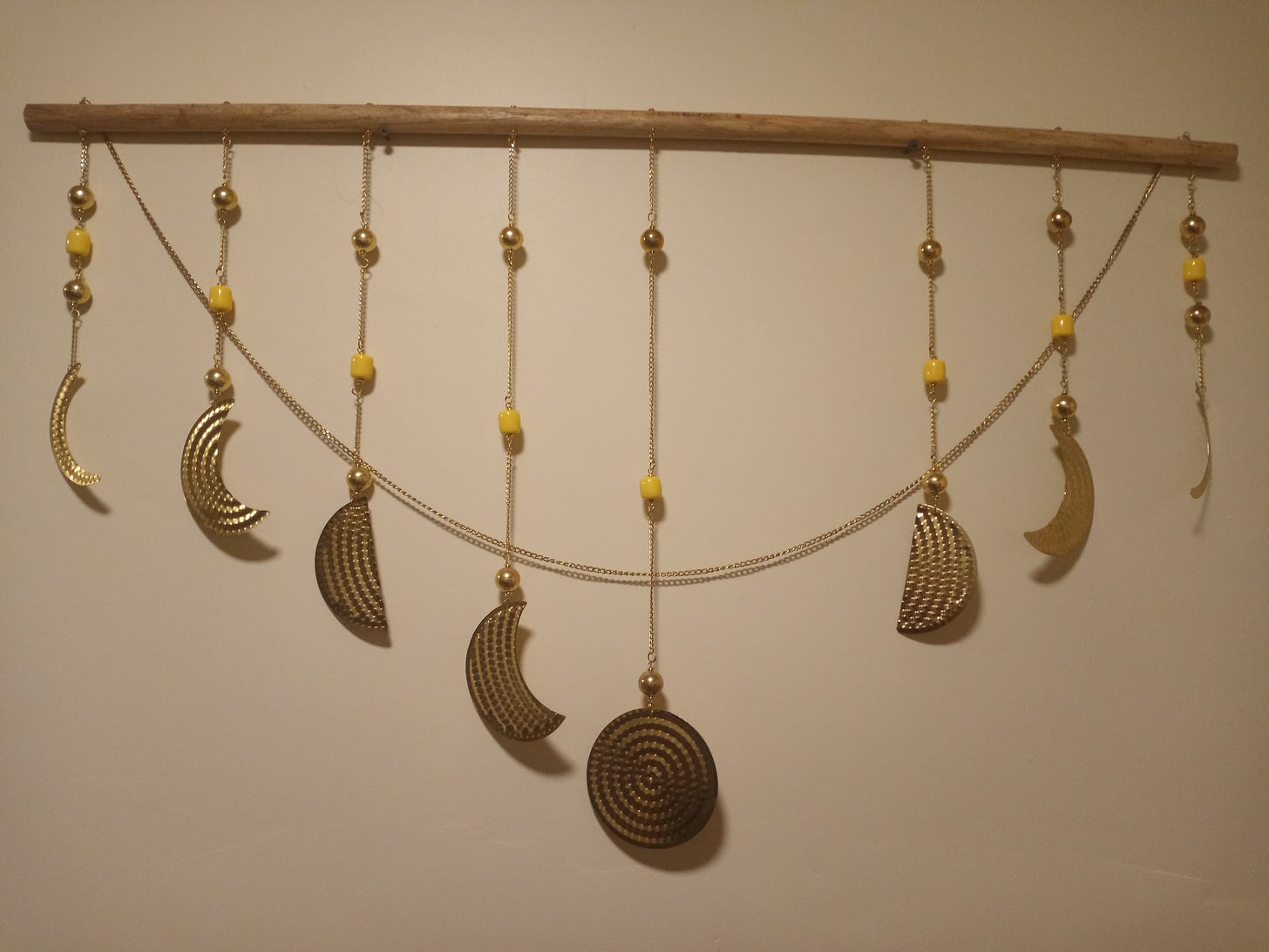 A metal and wood piece of wall art made to look like moon phases, but broken and missing one of the phases, like an eclipse.