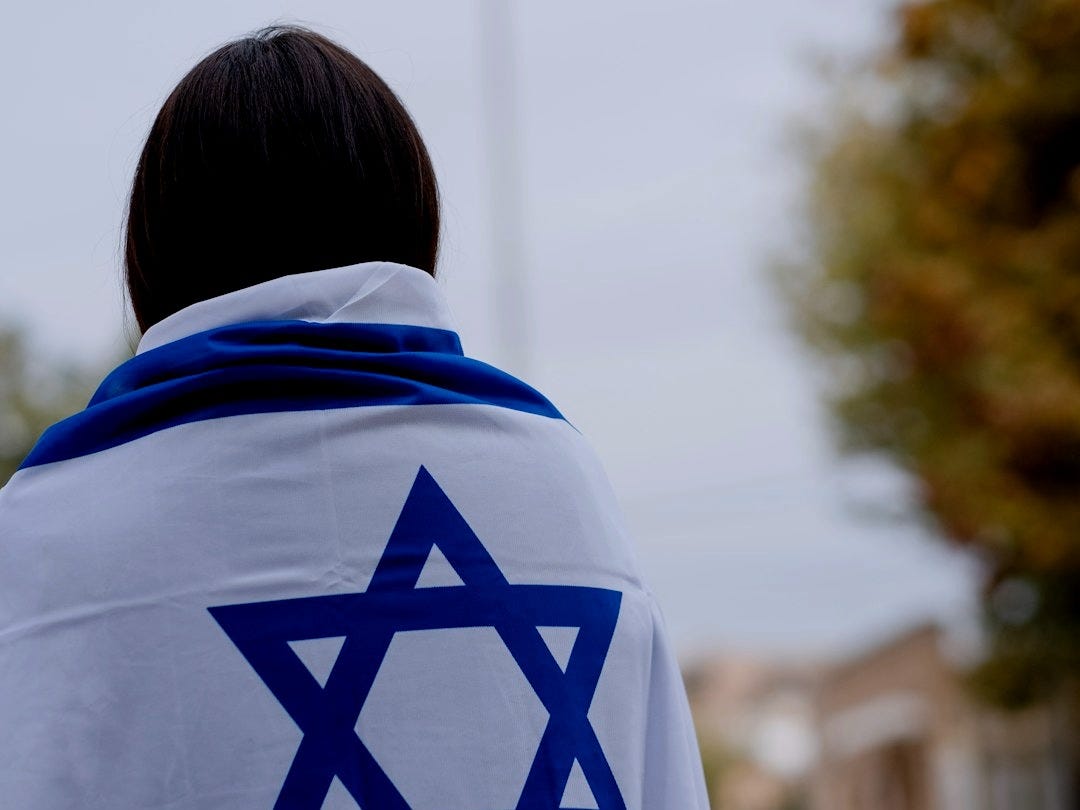 woman in white and blue hoodie standing near green trees during daytime