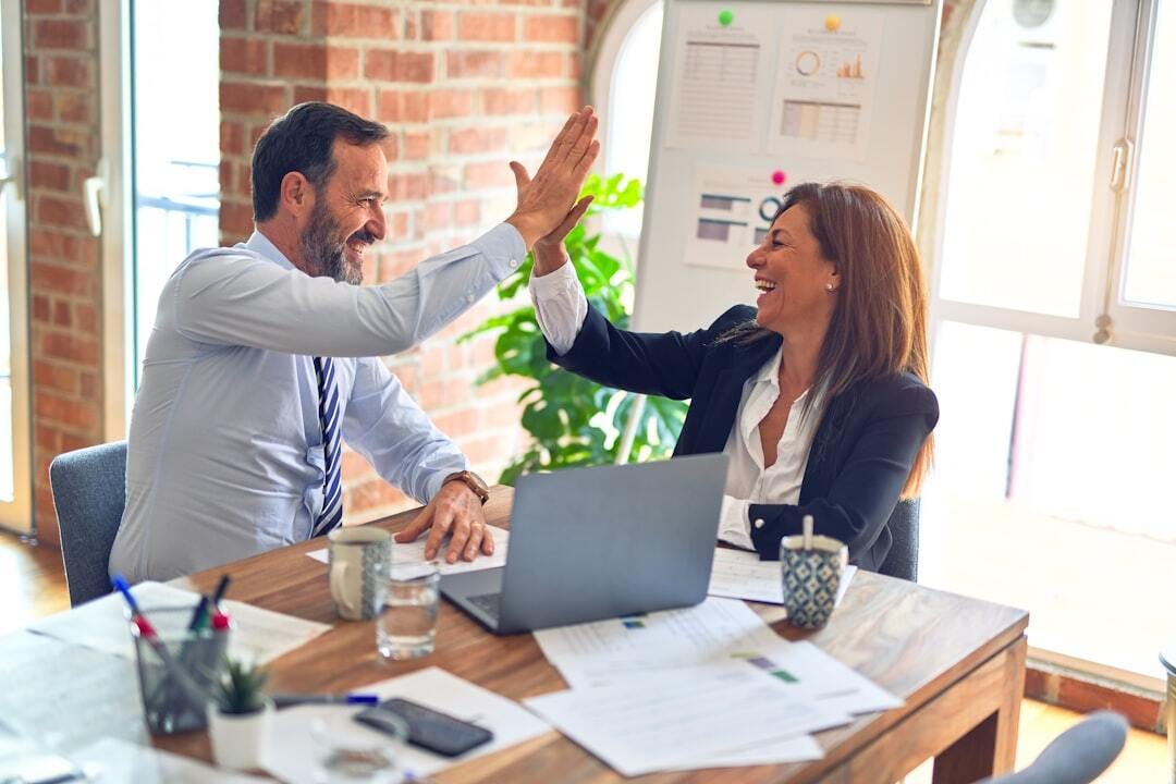 Two middle age business workers smiling happy and confident. Working together with smile on face hand giving high five at the office Two middle age business workers smiling happy and confident. Working together with smile on face hand giving high five at the office