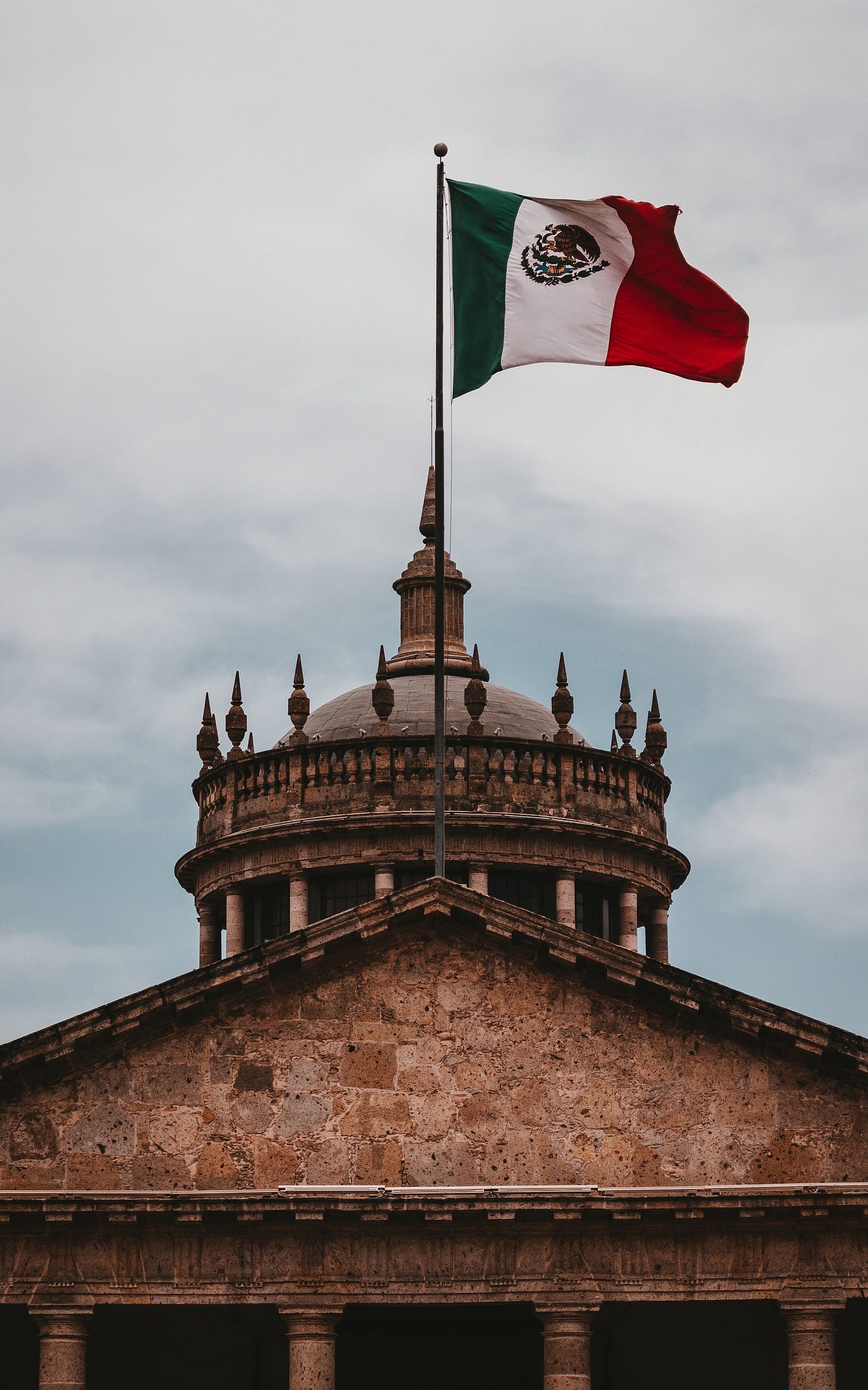 a mexican flag flying on top of a building a mexican flag flying on top of a building