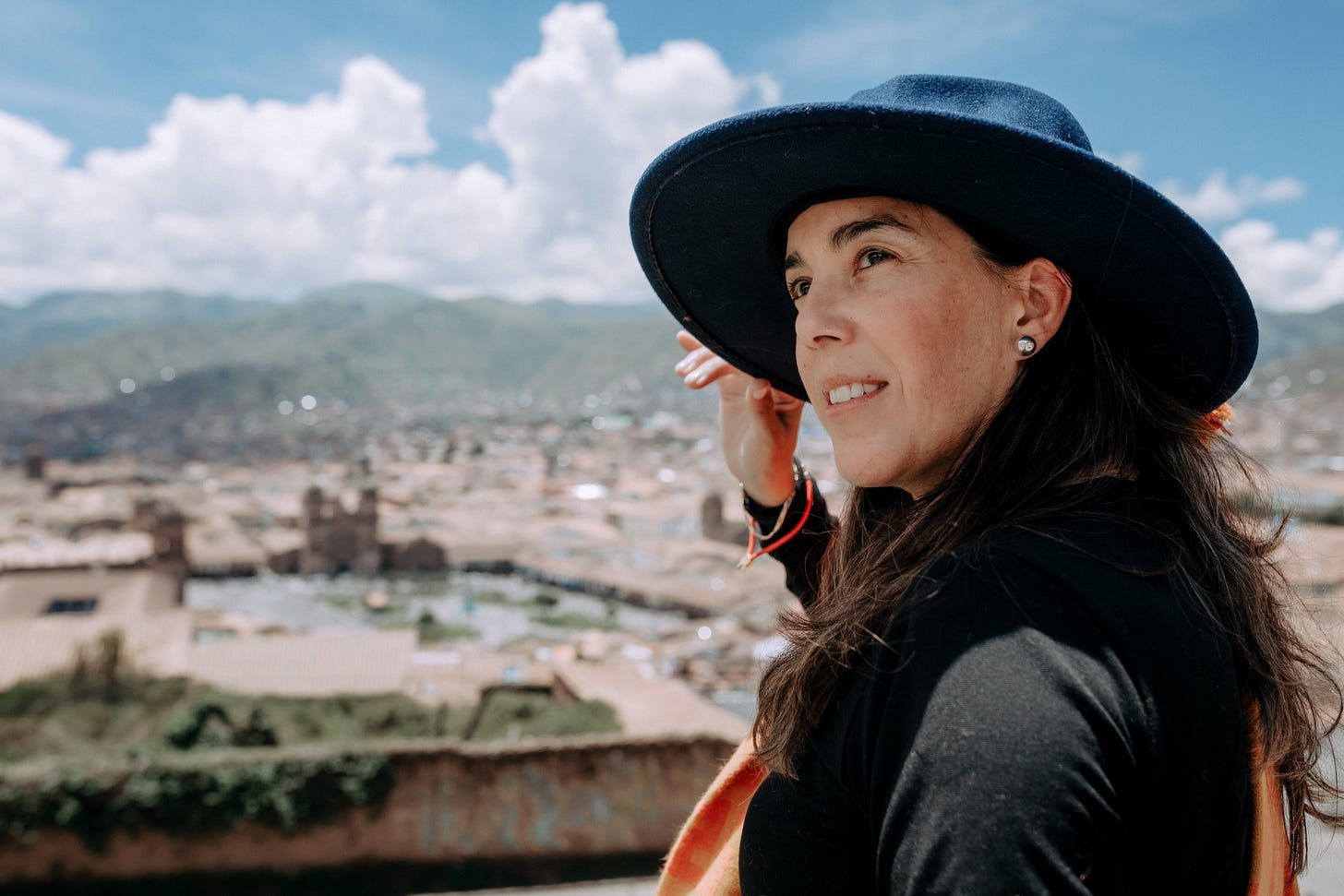 Picture of me sitting at top of a hill overlooking Cusco City - Perú. I am wearing my blue hat and orange manta (shawl) that was gifted by my mom.