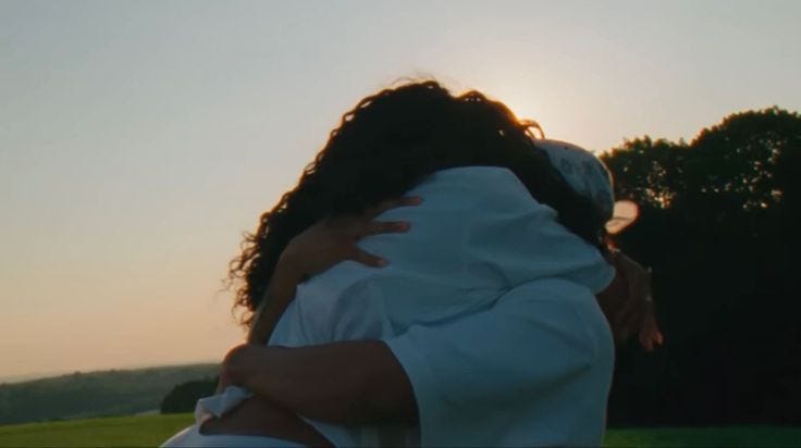 This may contain: two people hugging each other in the middle of a field