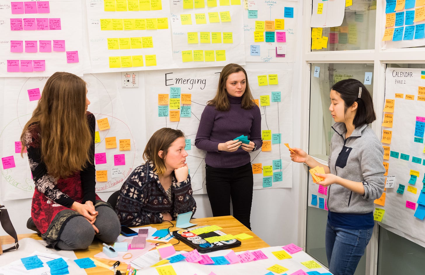 Four Olin students stand in a design studio discussing a project, surrounded by posters and graphs and dozens of sticky notes, processing ideas. Four Olin students stand in a design studio discussing a project, surrounded by posters and graphs and dozens of sticky notes, processing ideas.