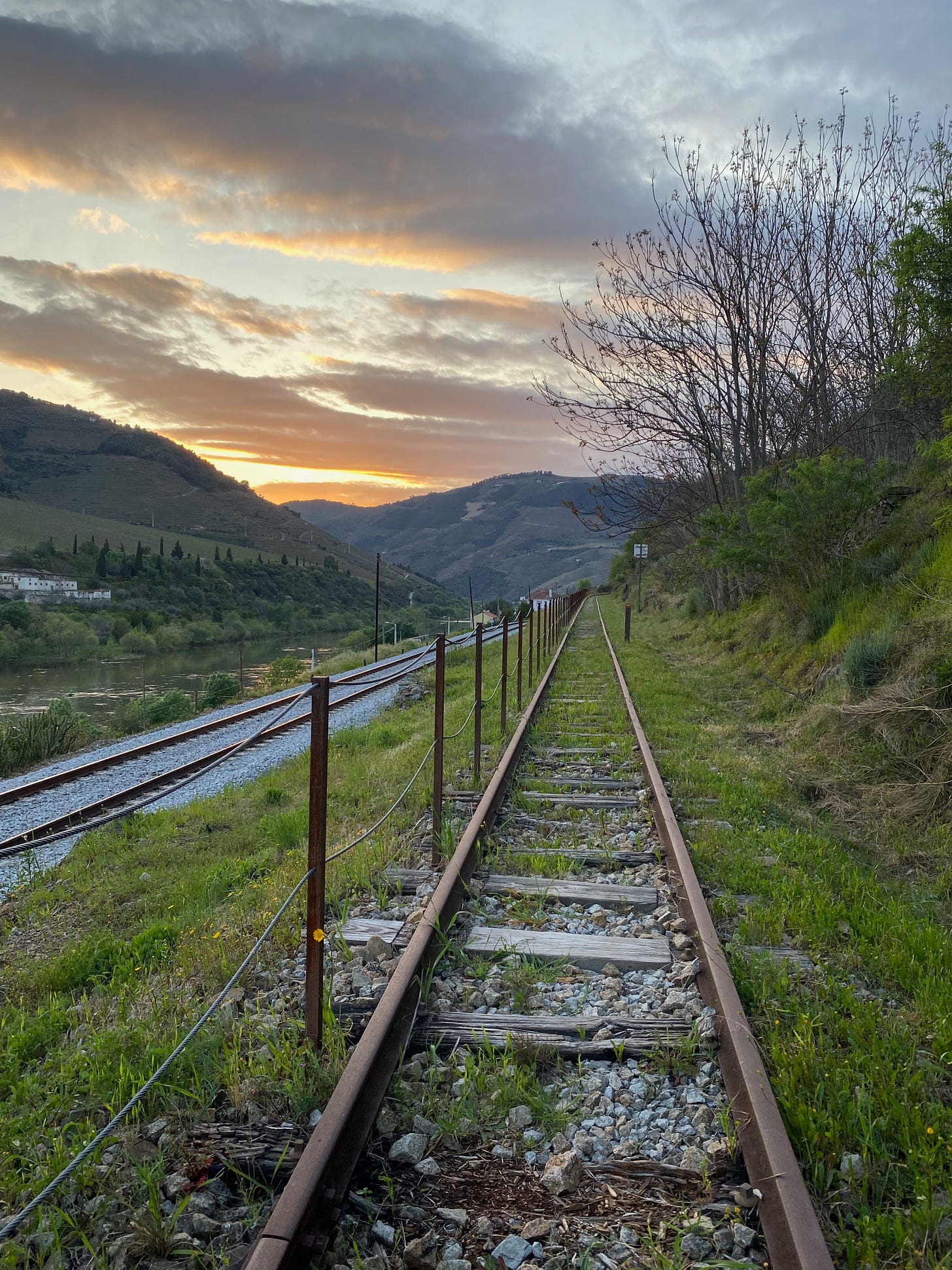 old railway lines pointing towards sunset in the mountains of the Douro valley at Foz Tua, Portugal